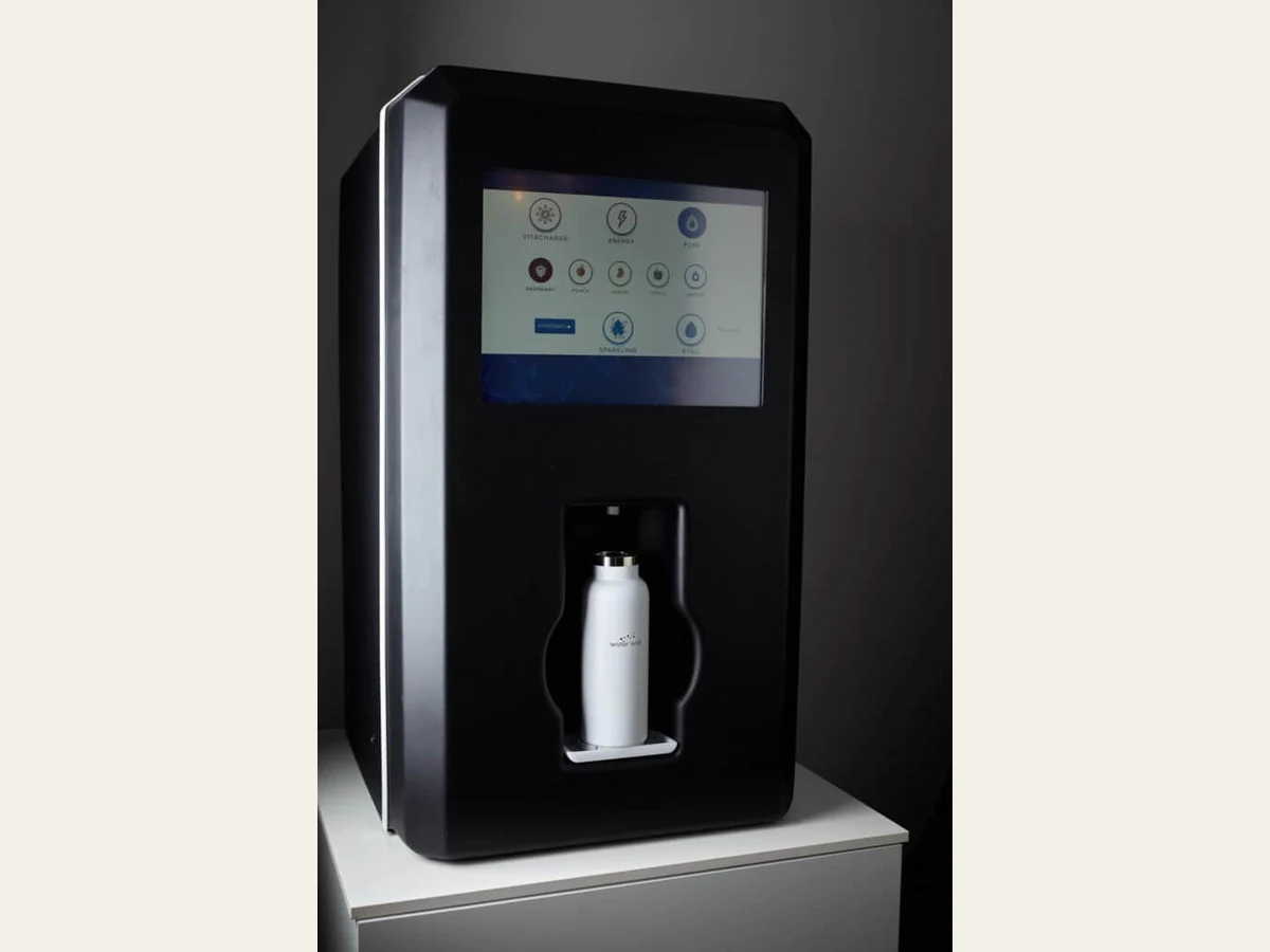 Waterwell water dispenser with touchscreen and a reusable bottle in the filling area.